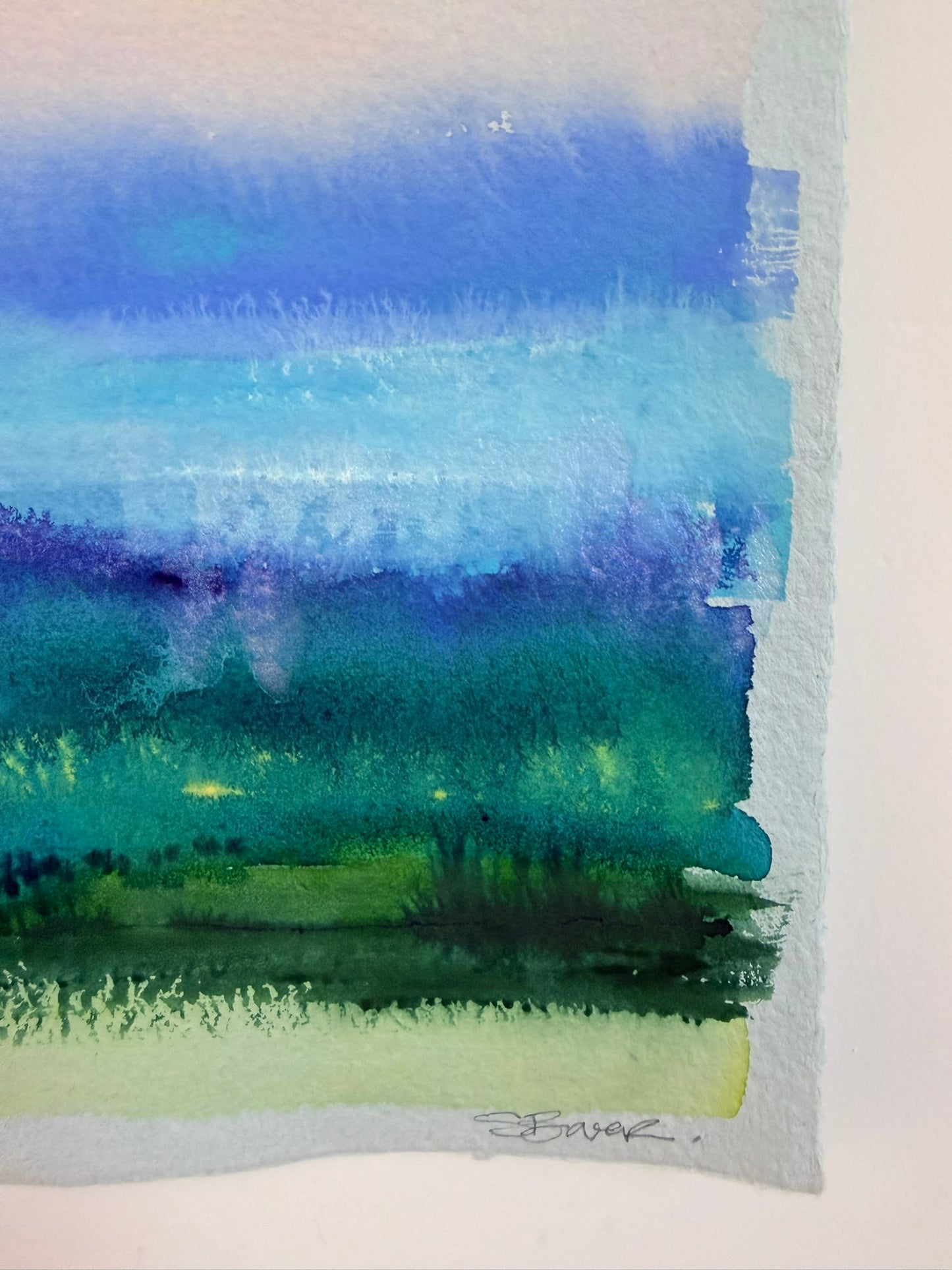 Watercolor landscape with blue, green, and purple hues on a white background